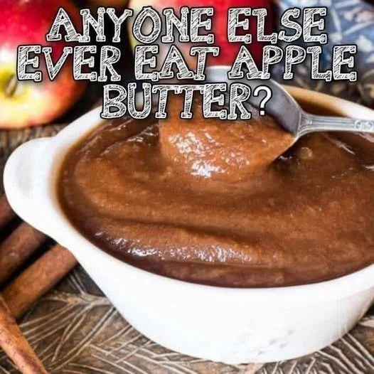 Homemade apple butter in a jar with fresh apples and cinnamon sticks